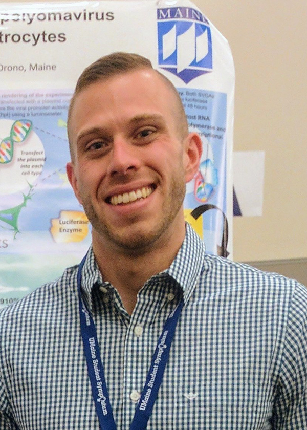 Michael Wilczek standing in front of his research poster.